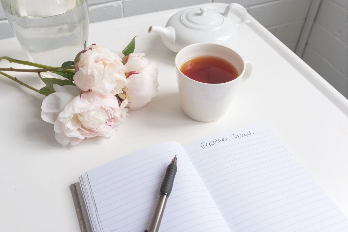 boost mental health with journaling, a journal, cup of coffee, and roses