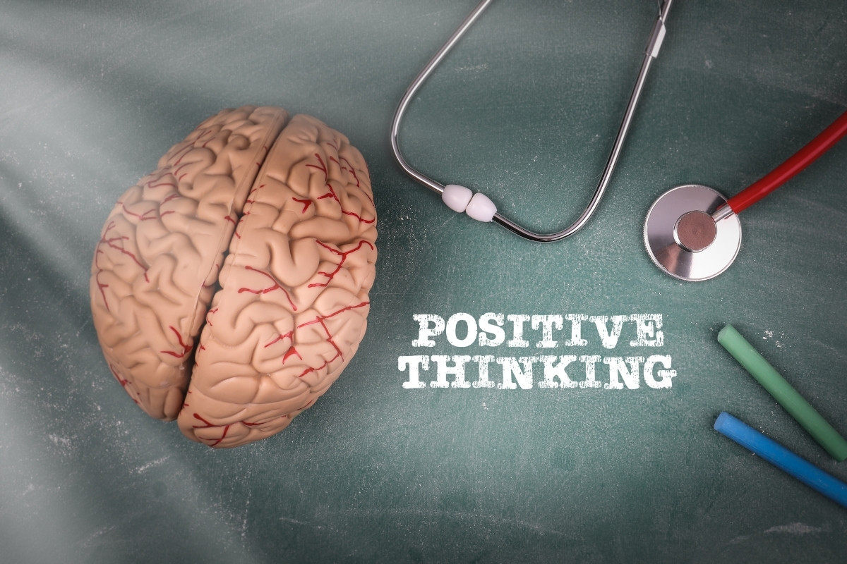 Positive mindset is represented by a chalk board with positive thinking written and a brain, stethoscope, and tools
